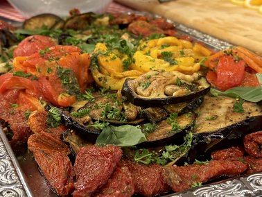 Antipasti-Platte mit gegrilltem Gemüse, Tomaten, Oliven und getrockneten Tomaten auf einem silbernen Tablett.