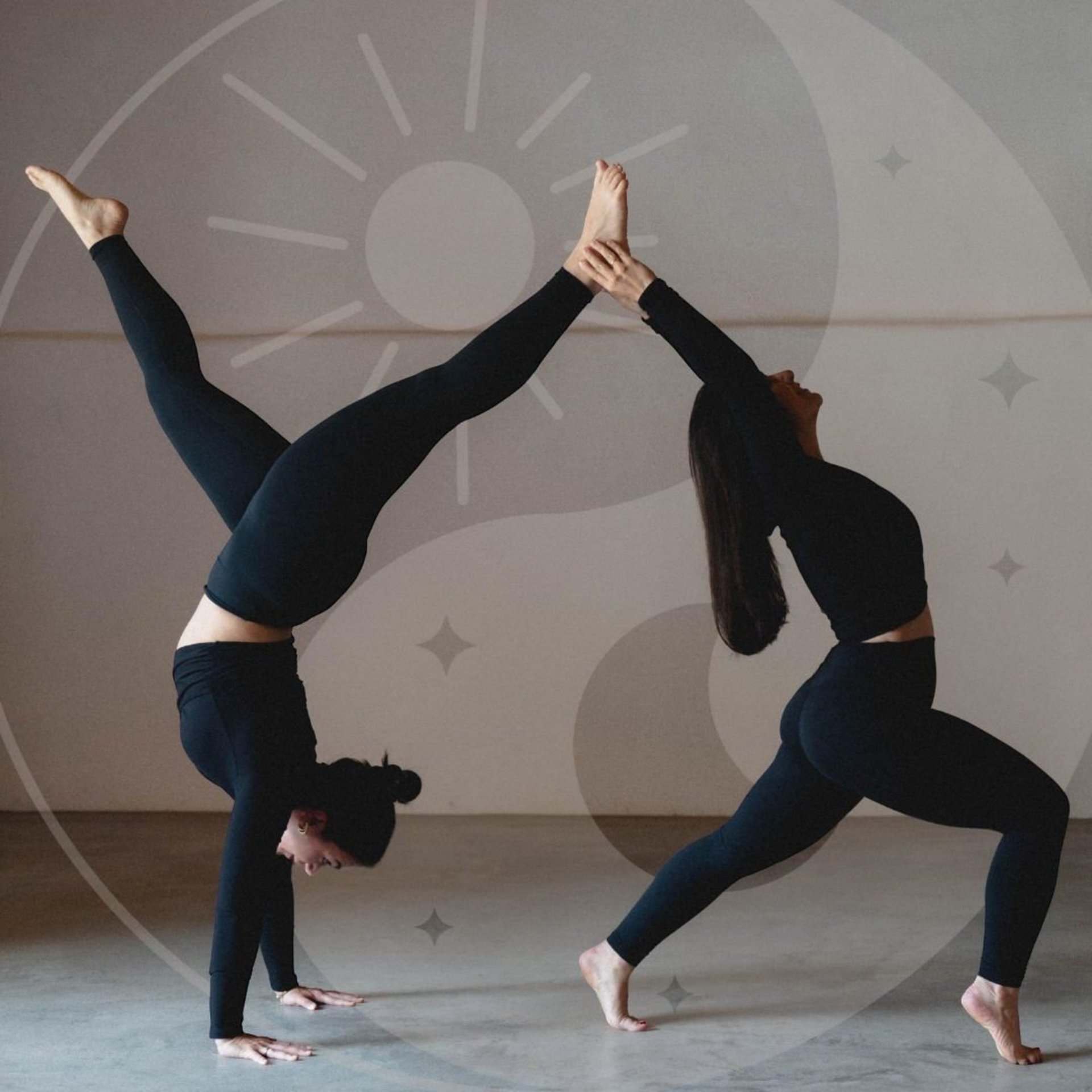 Zwei Personen in schwarzer Sportkleidung führen eine Partnerakrobatik-Übung aus, eine steht im Handstand, die andere hält deren Füße.