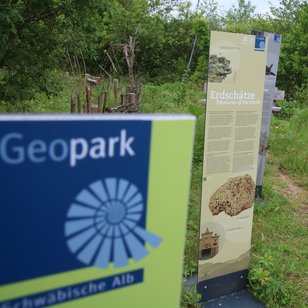 Informationsschilder im Grünen mit dem Titel 'Geopark Schwäbische Alb' und Details zu Erdschätzen