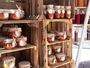 Holzkisten mit mehreren Gläsern gefüllt mit verschiedenen Marmeladen oder Eingemachtem, einige mit Stoffdeckeln und Bändern verziert.