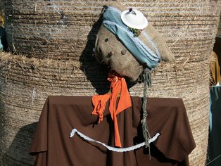  Kreative Vogelscheuche aus Stroh und Kleidung, die vor einem Strohballen steht.