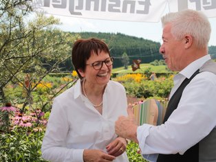 Zwei Personen bei fröhlicher Stimmung in einem blühenden Garten.