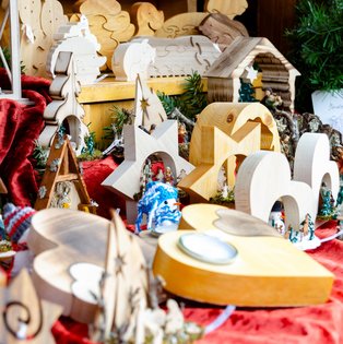 Verschiedene hölzerne Weihnachtsdekorationen und Figuren auf einem roten Tuch arrangiert