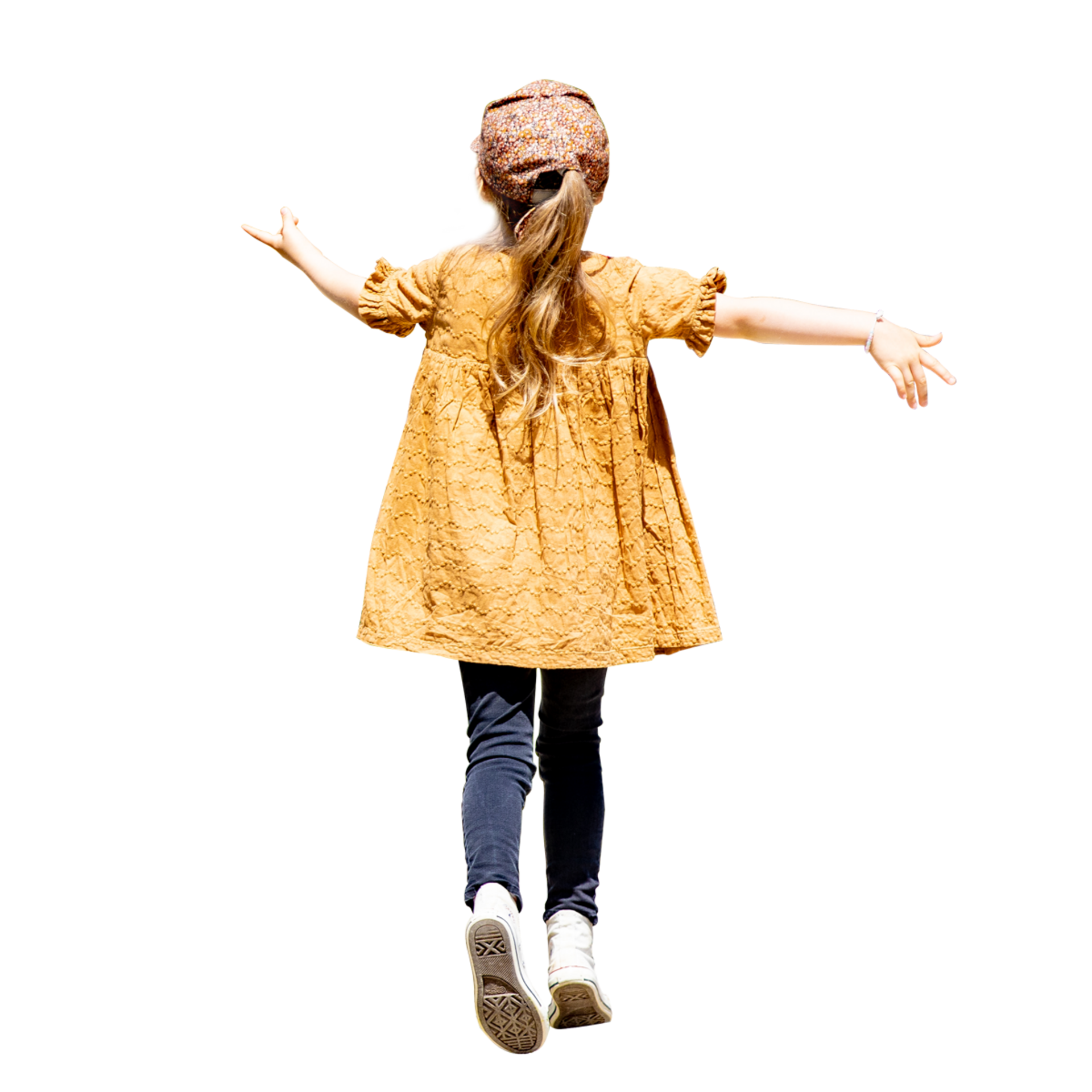 Junges Kind mit langen Haaren, das ein gelbes Kleid, Jeans und einen Hut trägt, geht mit ausgestreckten Armen im Freien spazieren.