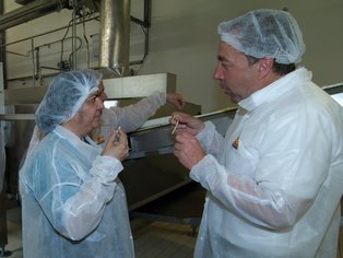 Zwei Personen haben die Schutzkleidung für die Produktion an und probieren Nudeln.
