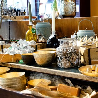 Verkaufsstand mit Holzschalen, Kerzen und einem Glasgefäß mit Preisschild auf einem Adventsmarkt