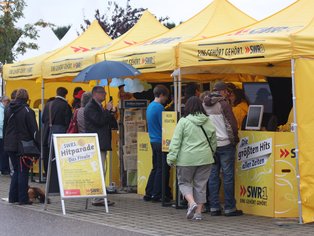 Menschen besuchen den SWR3 Pfännle Stand bei einer Veranstaltung.