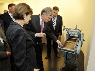 Mehrere Menschen stehen vor einer historischen Nudelmaschine.