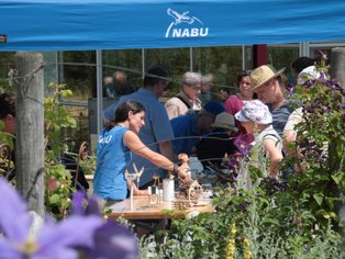 Menschen bei einer NABU-Veranstaltung im Garten, die an einem Tisch arbeiten.
