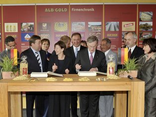 Horst Köhler unterzeichnet ein Dokument während einer feierlichen Zeremonie bei ALB-GOLD.