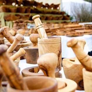 Mehrere hölzerne Mörser mit Stößeln auf einem Marktstand unter einem weißen Zelt