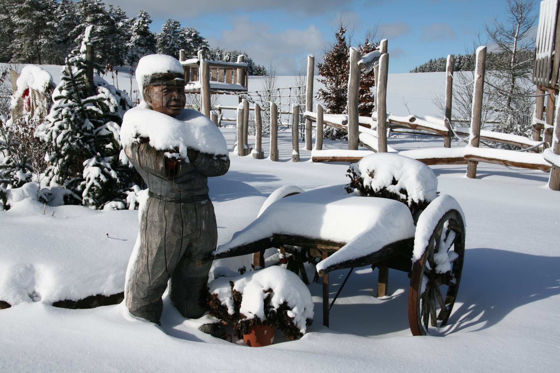 Eine Holzfigur, die mit Schnee bedeckt ist, in einer verschneiten Landschaft.
